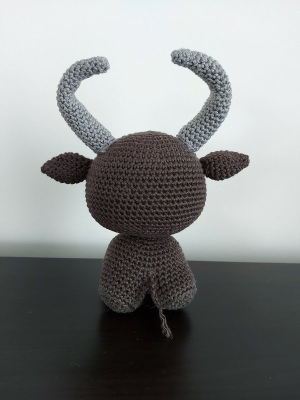 Rückansicht eines gehäkelten Amigurumi-Stiers, brauner Körper und graue Hörner