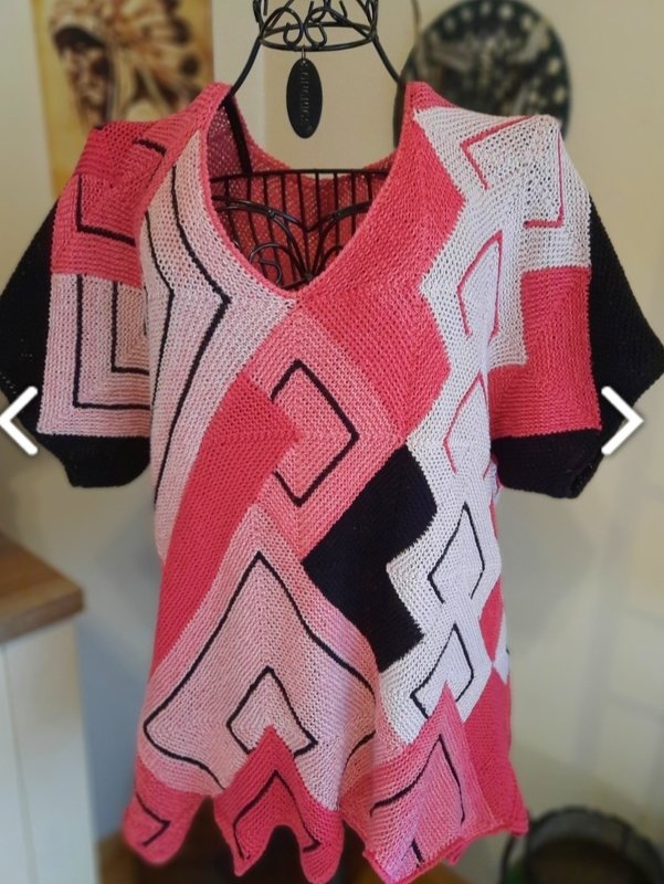 Gestricktes Damen‑Shirt in Pink, Weiß und Schwarz mit geometrischem Muster und V‑Ausschnitt auf Schneiderpuppe