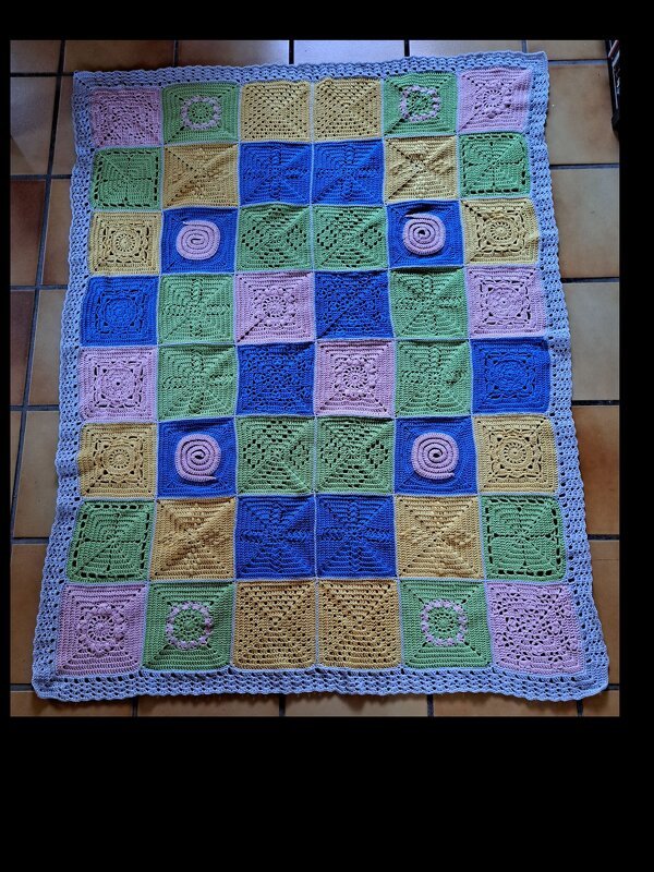 Patchwork-Häkeldecke in Pastell mit verschiedenen Quadraten und gewelltem Rand