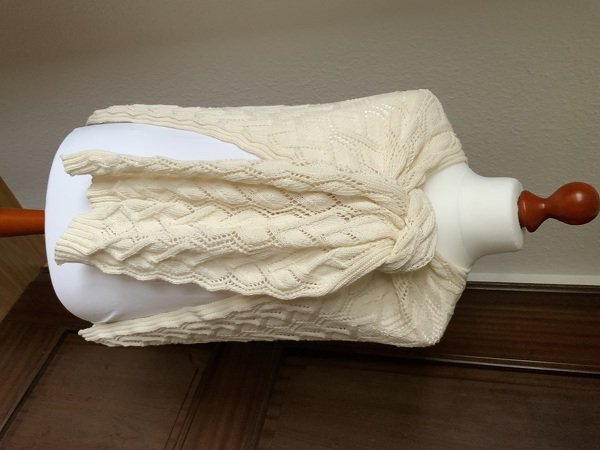 Nahaufnahme gestricktes Rechtecktuch mit Zopf- und Ajourstreifen auf Schaufensterpuppe