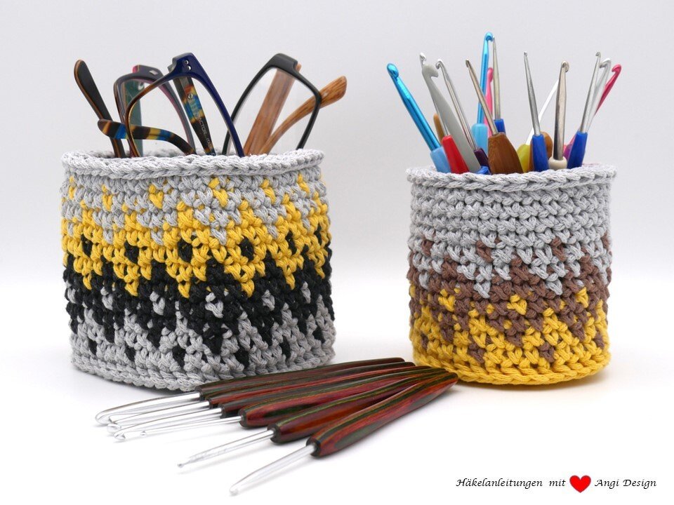 Zwei runde Aufbewahrungskörbe gehäkelt, gefüllt mit Häkelnadeln und Brillen