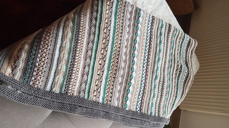 Gehäkelte Decke mit schmalen Streifen in Creme, Grau und Mint, mit grauer Einfassung, auf einem Sofa drapiert