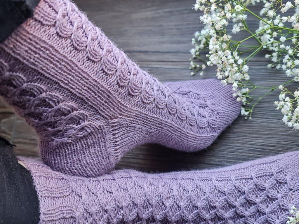 Nahaufnahme von fliederfarbenen Stricksocken mit Rippbündchen und ausgearbeiteter Ferse