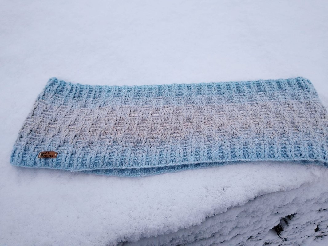 Gehäkelter Loopschal hellblau-beige mit Korbgeflechtmuster auf Schnee