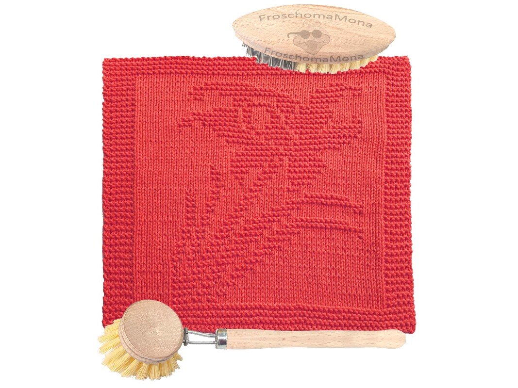 Rotes gestricktes Tuch mit Hasenmotiv, daneben zwei Holzbürsten