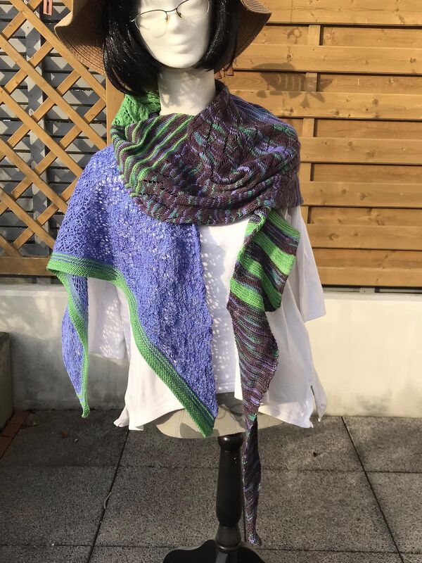 Mannequin trägt gestricktes asymmetrisches Dreieckstuch in Lila und Grün mit Lochmuster und Streifen