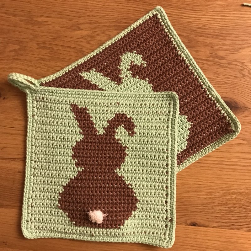 Zwei quadratische gehäkelte Topflappen in Mintgrün und Braun mit Hasen-Silhouette und Bommel