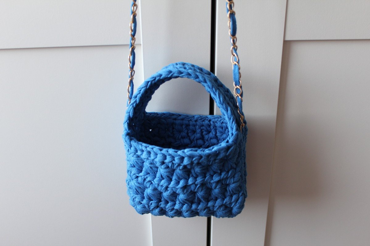 Quadratische blaue Mini-Häkel­tasche mit rundem Griff und Kettenriemen