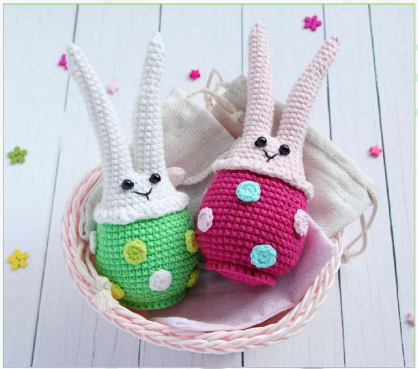 Zwei gehäkelte Hasen‑Amigurumi mit punktiertem ei‑förmigen Körper in einem Korb