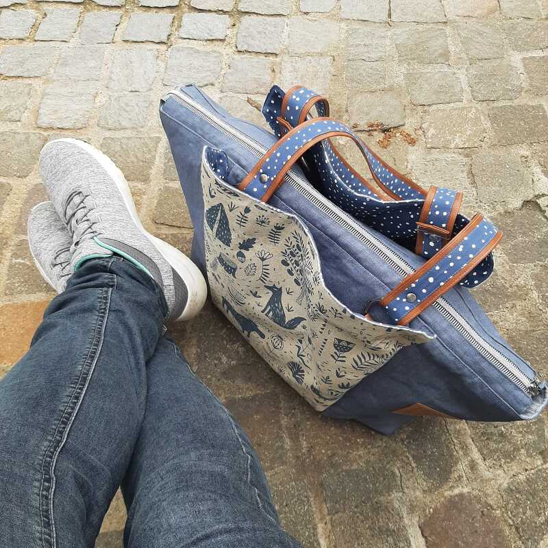 Blaue Denim-Jeanstasche mit Fuchs- und Waldmotiv, gepunkteten Trägern und Reißverschluss auf Kopfsteinpflaster