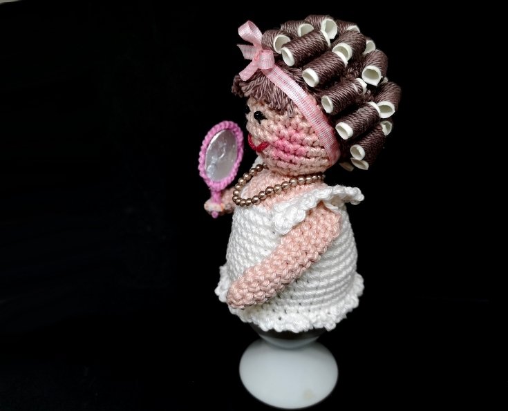 Gehäkelter Eierwärmer in Damenform mit Lockenwicklern, rosa Haarband und Handspiegel