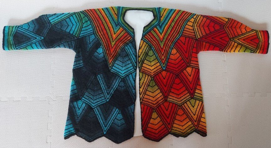 Gestrickte Damenjacke, flach liegend, mit geometrischem V-Muster in Blau-Grün und Rot-Orange
