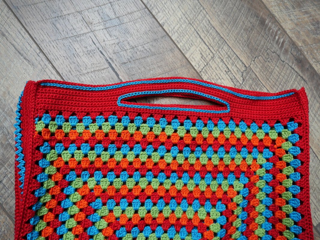 Gehäkelte rechteckige Henkeltasche mit bunten Granny-Clustern und integriertem Griffloch