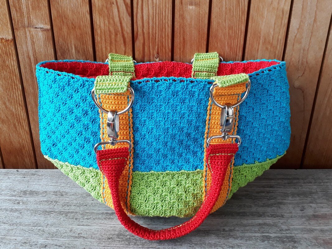 Turquoise and lime green crocheted tote with orange handles, silver clip hardware and red lining