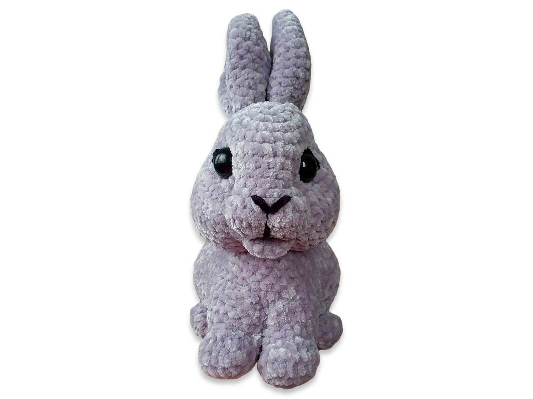 Lavender crochet amigurumi rabbit sitting upright, plush textured yarn, long ears and dark eyes