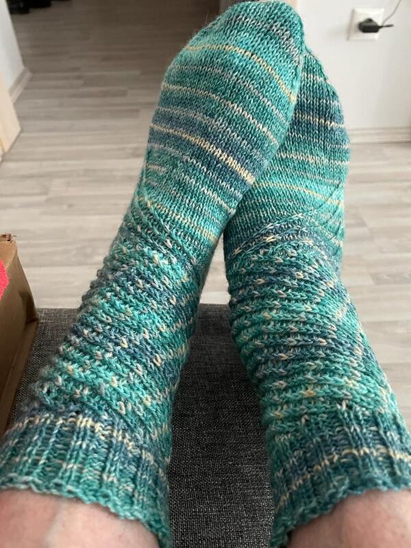 Nahaufnahme handgestrickter türkiser Socken mit strukturiertem Schaft und glatt gestricktem Fuß