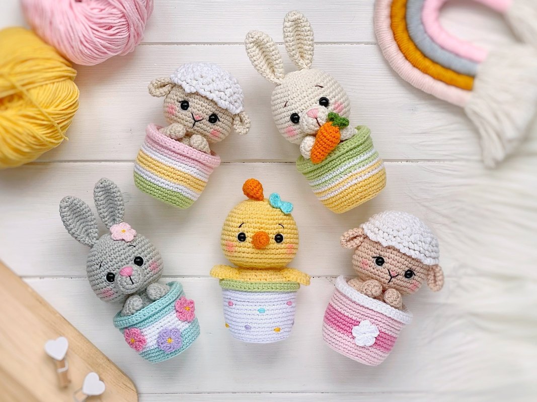 Five amigurumi Easter animals—two bunnies, two lambs, and a chick—each in a striped crochet cup.