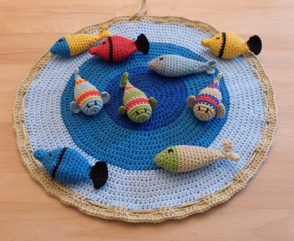 Runder gehäkelter Teppich in Blautönen mit bunten gehäkelten Fischen darauf