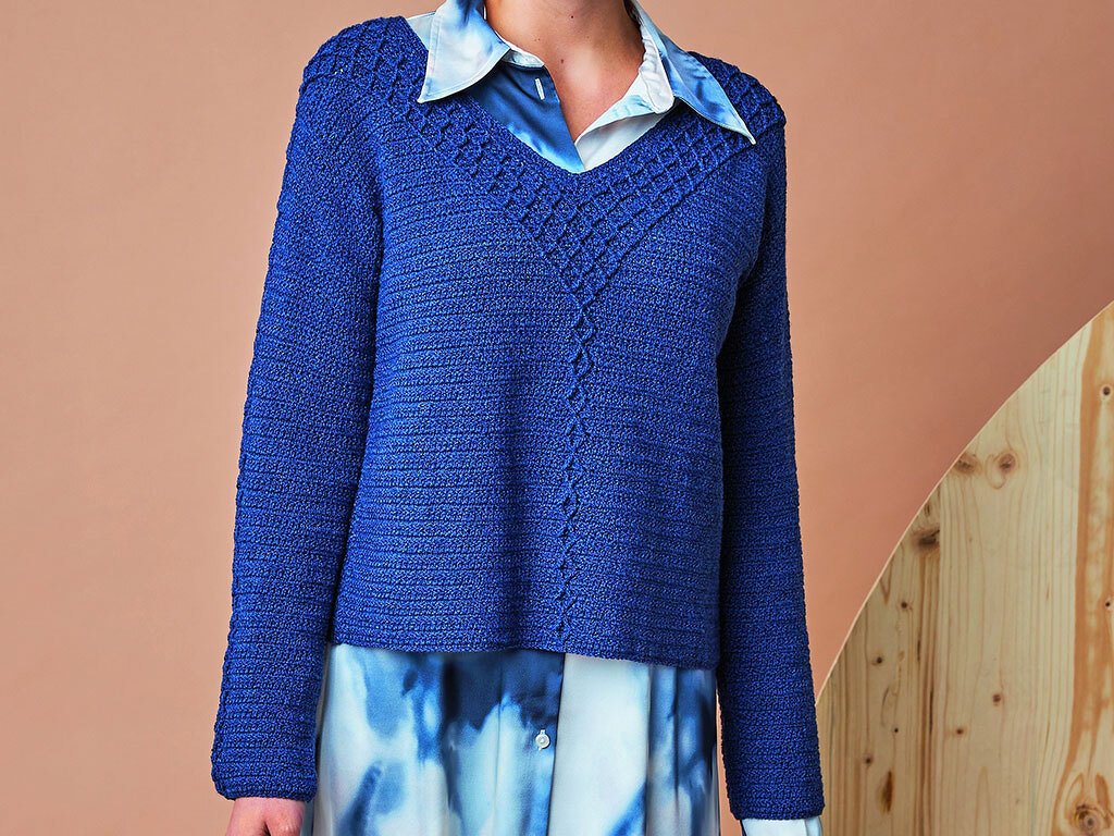 Frontalansicht eines gehäkelten kobaltblauen Pullovers mit V-Ausschnitt und zentraler Ziernaht