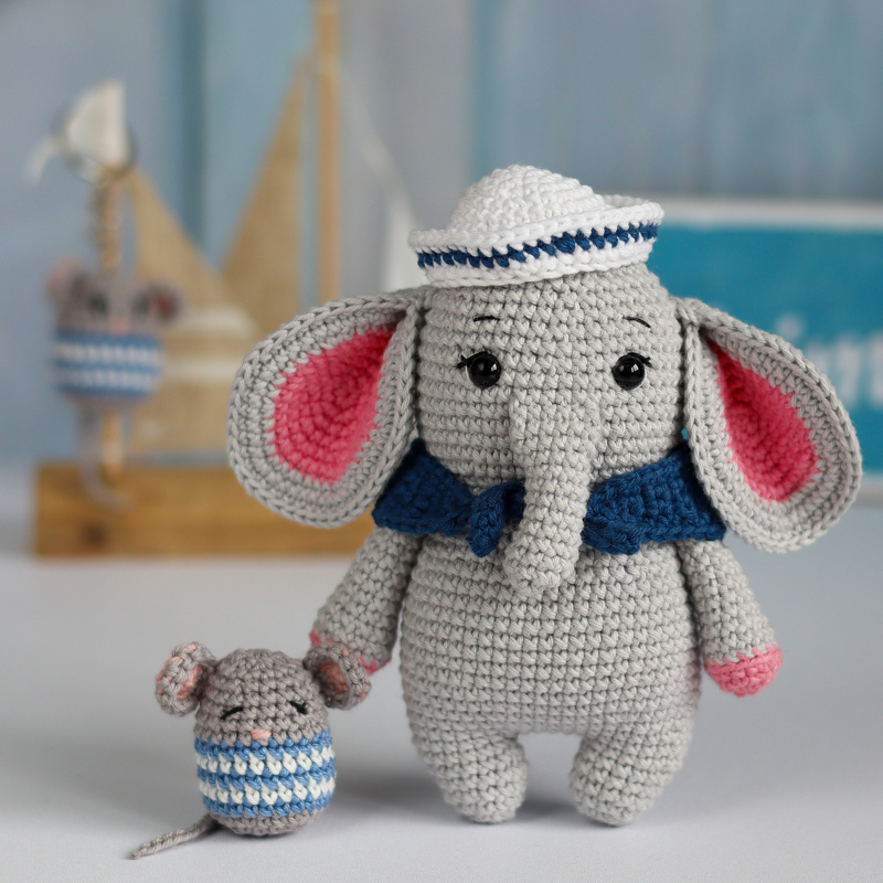 Gehäkelter grauer Elefant mit rosa Ohren, blauem Kragen und weiß-blauem Matrosenhut neben kleiner gestreifter Maus