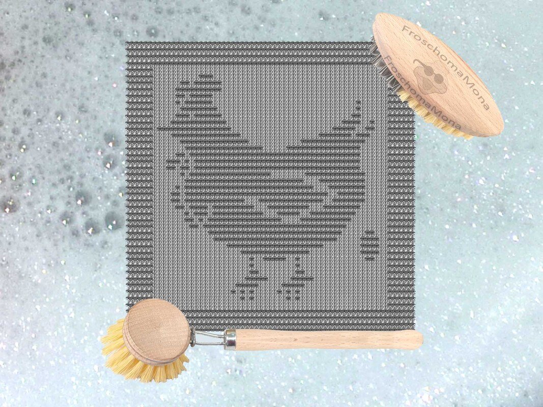 Gestricktes, quadratisches Spültuch in Grau mit Hühner‑Motiv auf schaumigem Hintergrund und zwei Holzbürsten.