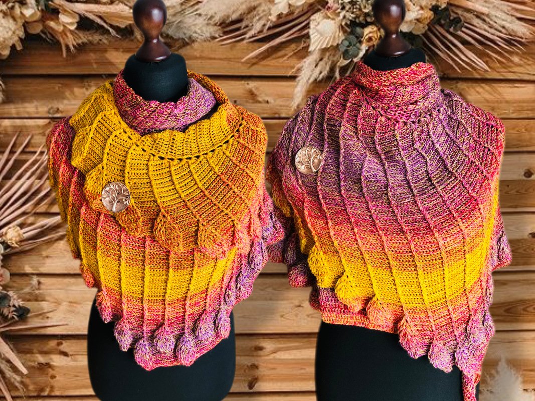 Zwei gehäkelte Tücher in Gelb, Pink und Lila mit Schuppenmuster und Baum-des-Lebens-Broschen vor Holzpaneelen.