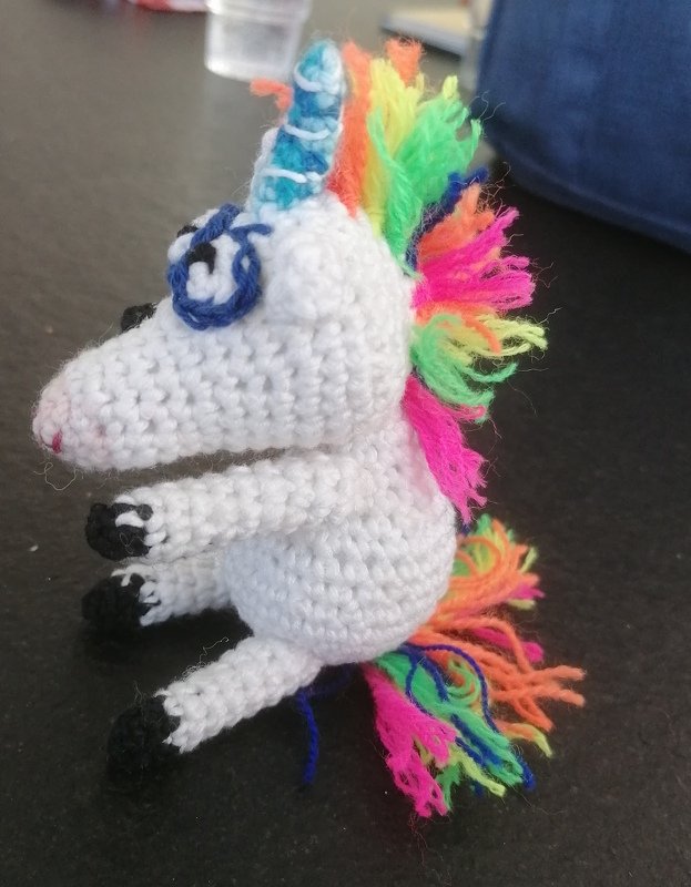 Gehäkeltes weißes Einhorn-Amigurumi mit regenbogenfarbener Mähne und Schweif, Seitenansicht