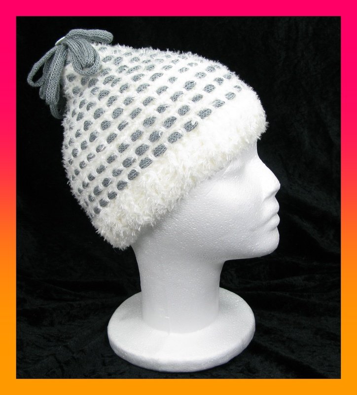 Weiß-graue gehäkelte Kindermütze mit flauschigem Rand und grauem Knoten auf Styroporkopf