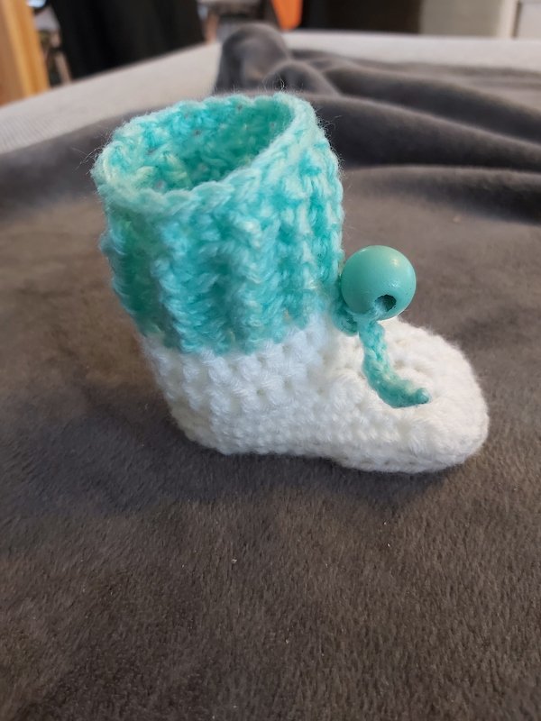 Gehäkelter Babyschuh weiß mit türkisfarbener Umschlagkante und Perle