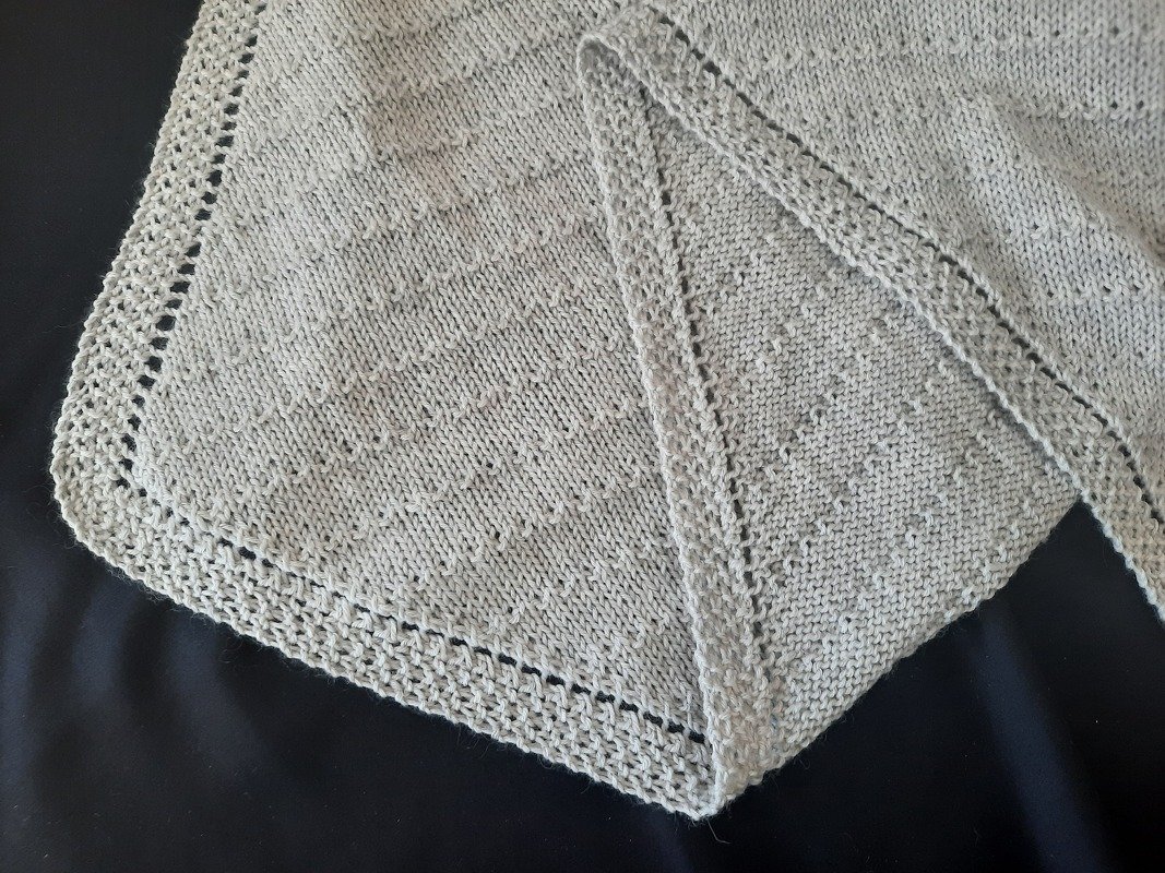 Hellgraues gestricktes Dreieckstuch mit feinem Strukturmuster und Lochrand