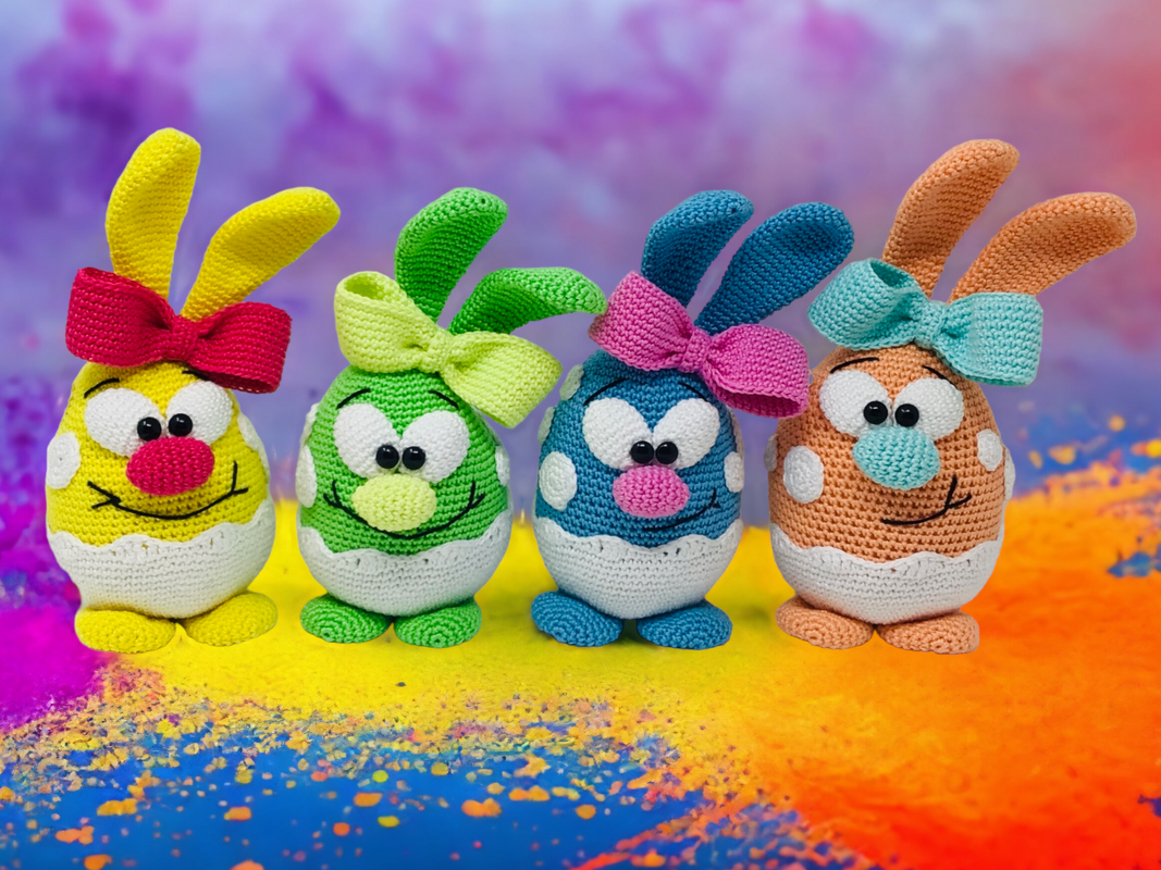 Four egg-shaped crocheted bunnies in yellow, green, blue and orange with bows and polka dots