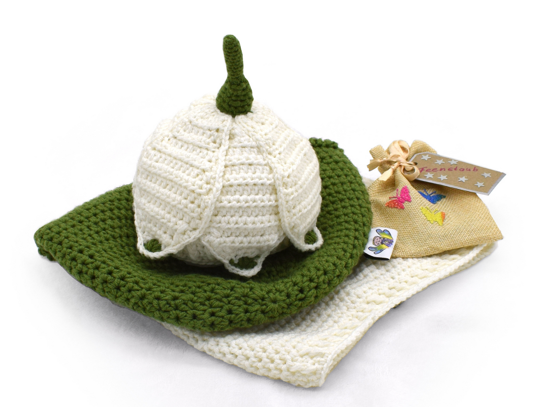 Gehäkeltes Neugeborenen-Set mit cremefarbener Mütze, grüner Unterlage, heller Decke und kleiner Geschenktasche