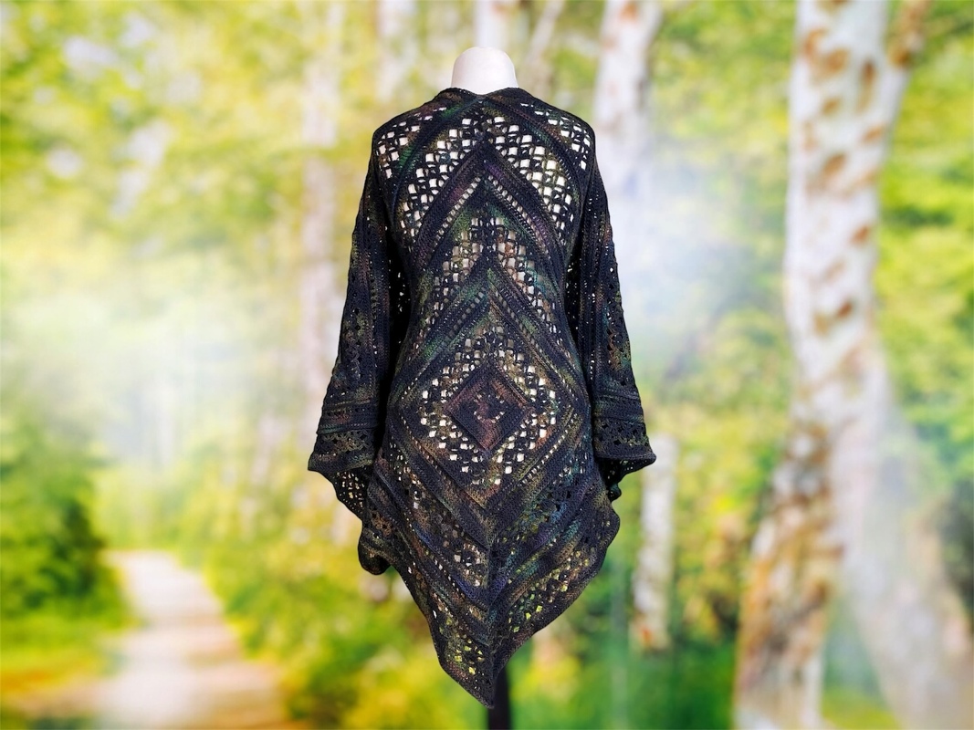 Dark crochet lace shawl with central diamond motif and pointed hem on a mannequin
