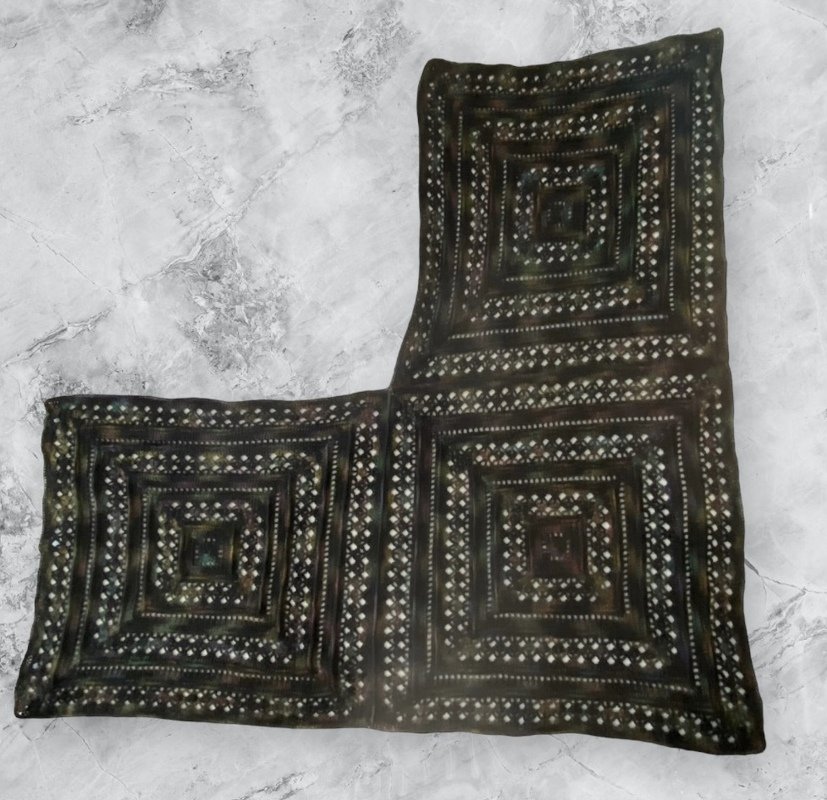 Dark L-shaped crocheted shawl of joined concentric square panels with light accent stitches