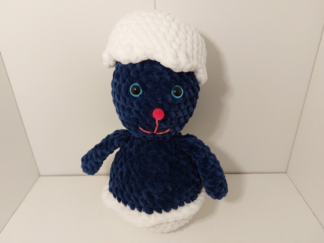 niedlicher dunkelblauer Amigurumi-Hase mit weißer Mütze und rosa Nase