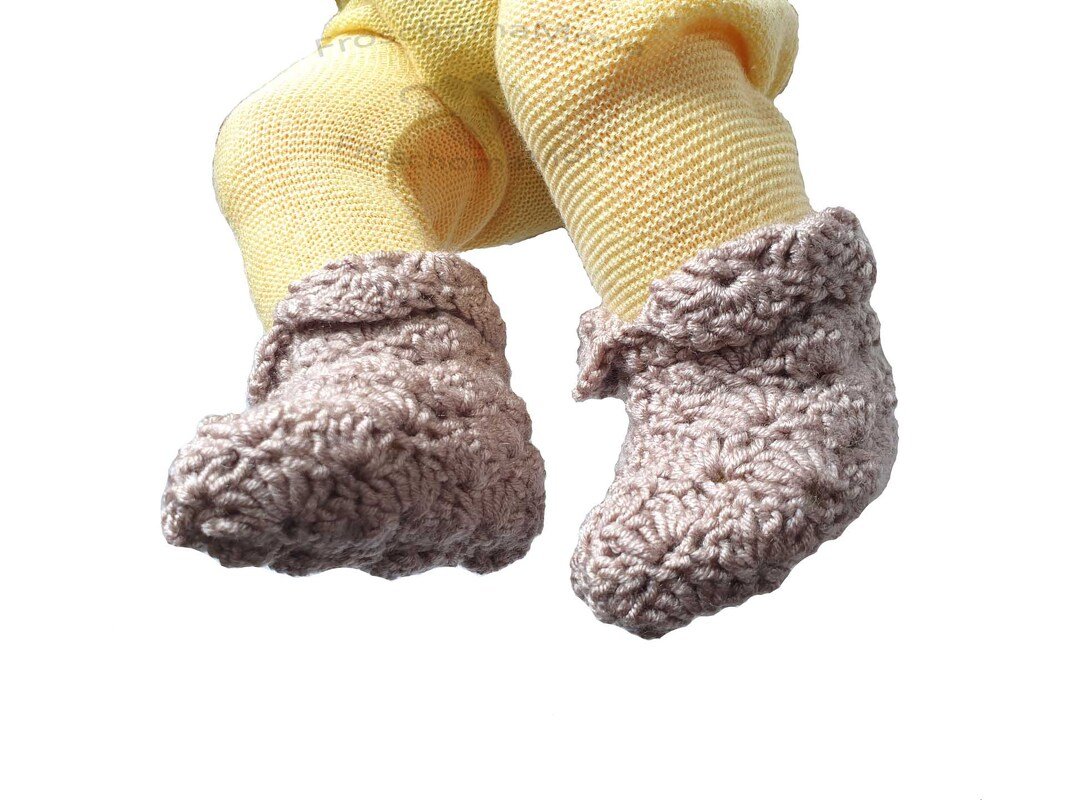 Gehäkelte rosa Babyschuhe an Babybeinen mit gelben Strumpfhosen