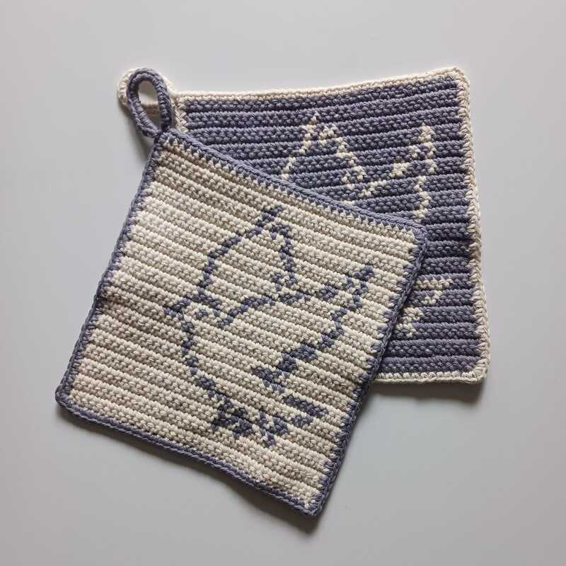 Zwei handgehäkelte quadratische Topflappen in Grau und Creme mit Blatt- und Baum-Motiv, eine mit Aufhängeschlaufe.