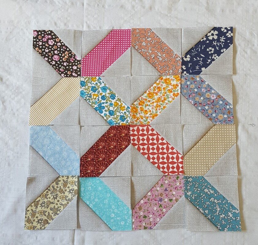 Patchwork-Block mit diagonalen bunten Streifen auf hellem Grund