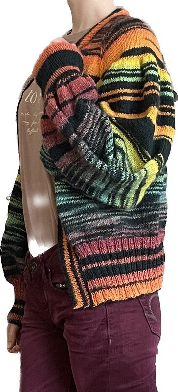 Offen getragene, bunte Strickjacke mit horizontalen Streifen über hellem Oberteil