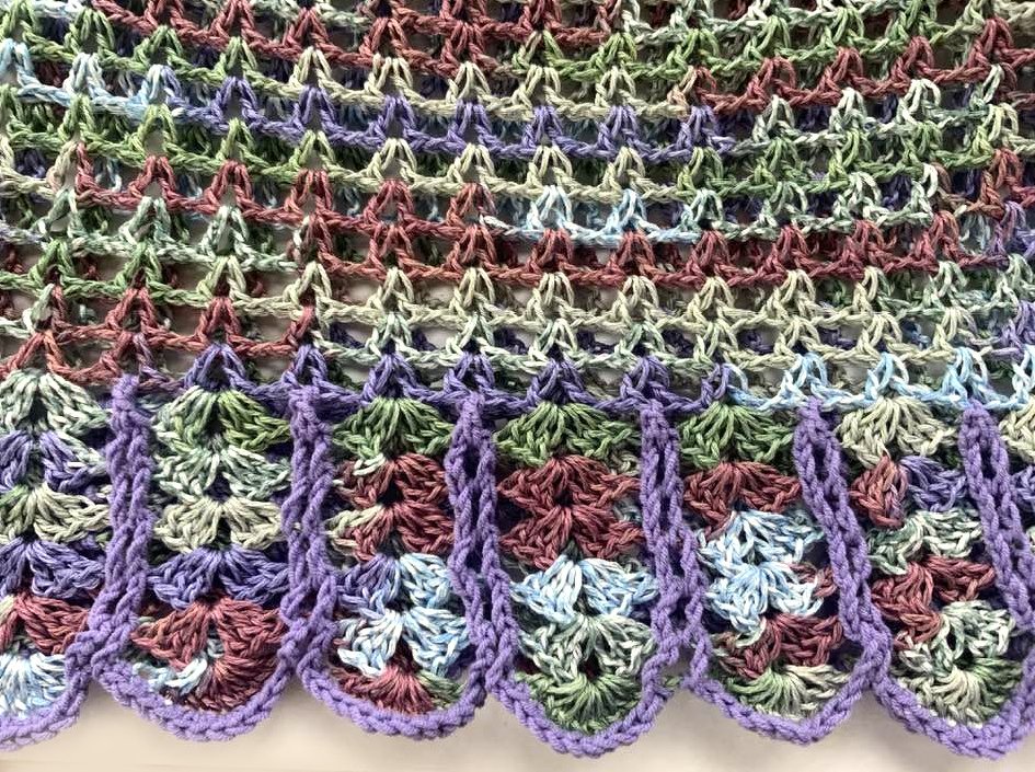 Nahaufnahme gehäkeltes Lochmuster in Pastellfarben mit Muschelsaum
