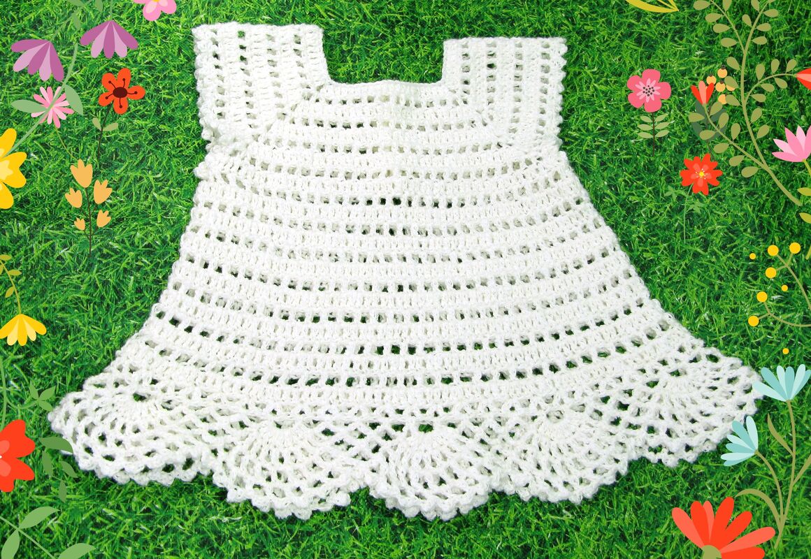 Weißes gehäkeltes Babykleid mit Muschelsaum auf grünem Rasen