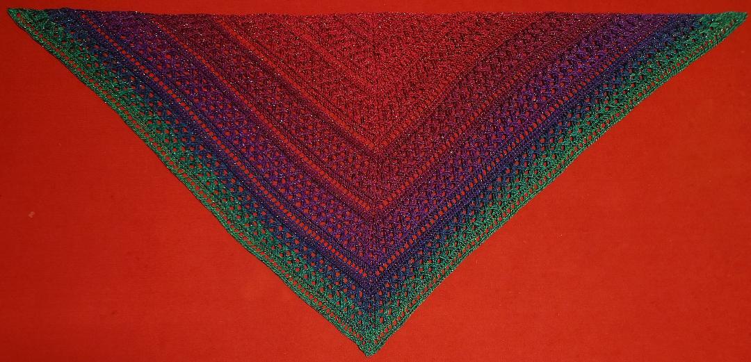 Gehäkeltes Dreieckstuch in Rot, Lila und Grün mit offenem Spitzenmuster auf rotem Hintergrund