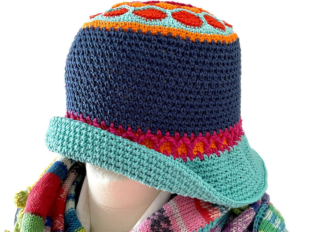 Bunter gehäkelter Damenhut mit breiter helltürkiser Krempe, dunkelblauem Kopfteil und pink-orangefarbenen Details