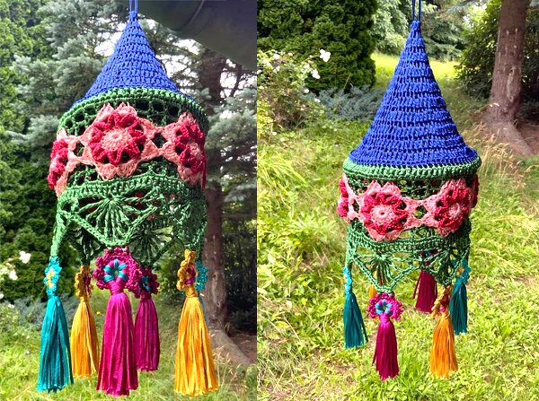 Bunter gehäkelter Lampion mit Blumenapplikationen und bunten Quasten vor grünem Gartenhintergrund