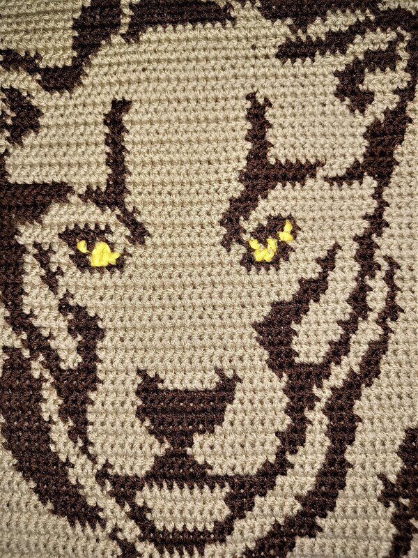 Gehäkeltes Pixelmuster eines Tigerkopfes in Beige und Braun mit gelben Augen