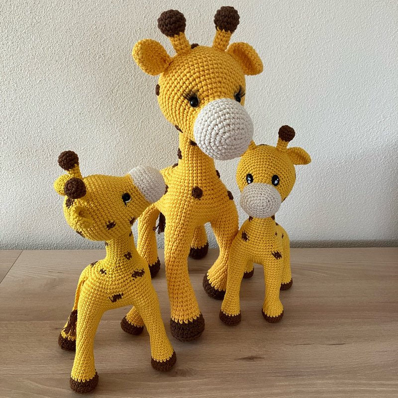 Drei gehäkelte Amigurumi-Giraffen in Gelb mit braunen Flecken und weißen Schnauzen