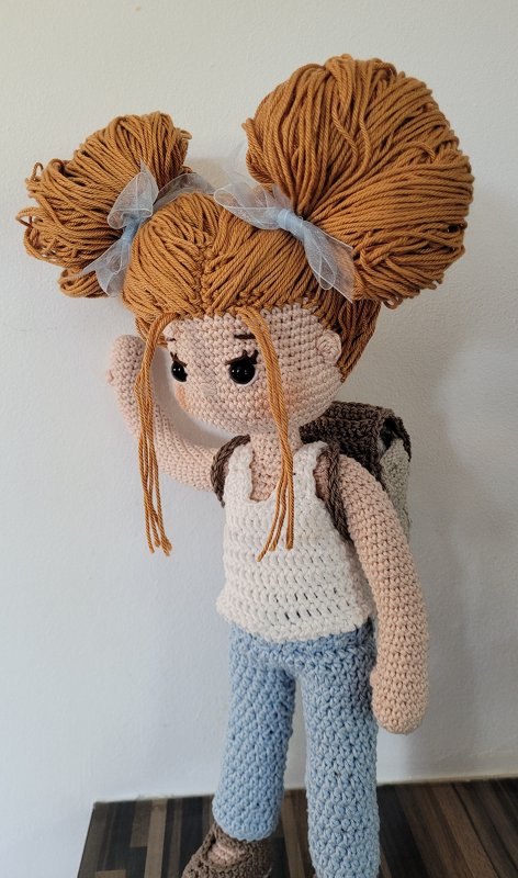 Gehäkelte Amigurumi-Puppe mit zwei großen Haarknoten, Schleifen und Rucksack