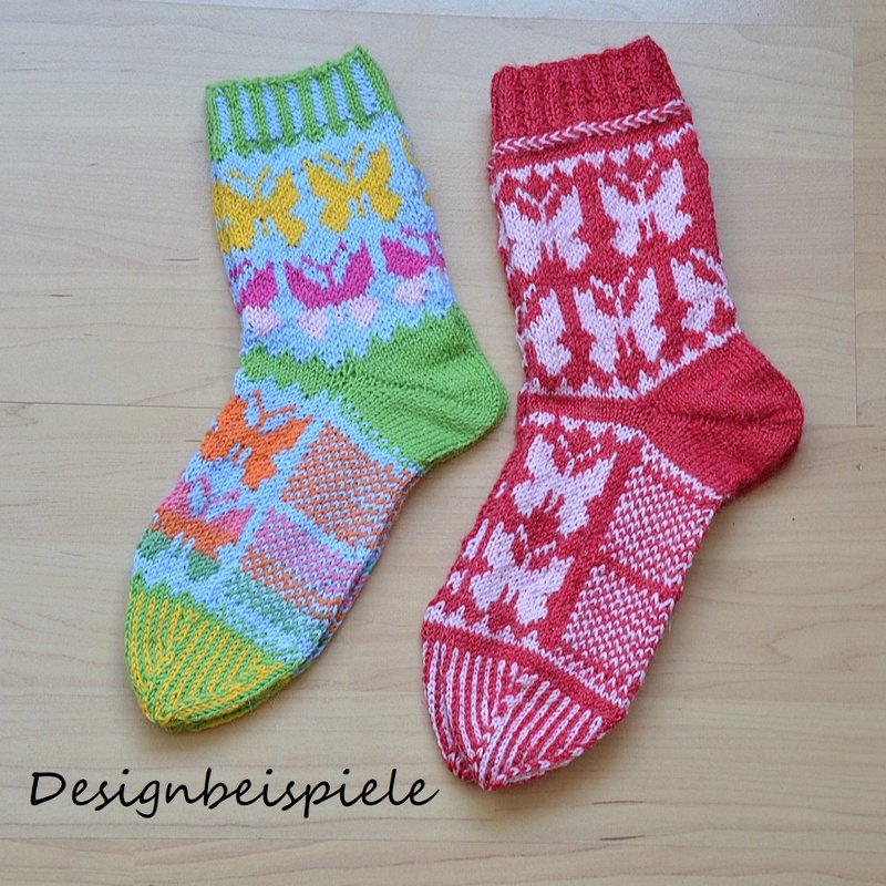 Zwei gestrickte Socken mit Schmetterlingsmuster, eine bunte Socke links und eine rot-weiße Socke rechts auf hellem Holz