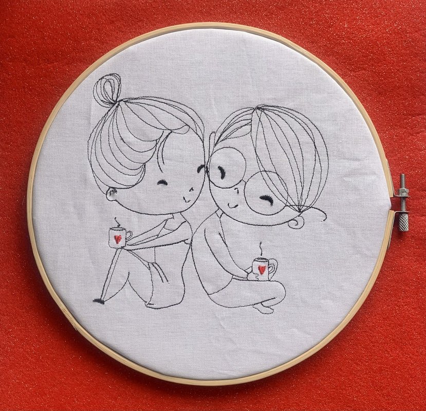 Linienstickerei im Holzrahmen: zwei sitzende Personen Rücken an Rücken mit Tassen und kleinen roten Herzen auf weißem Stoff vor rotem Hintergrund