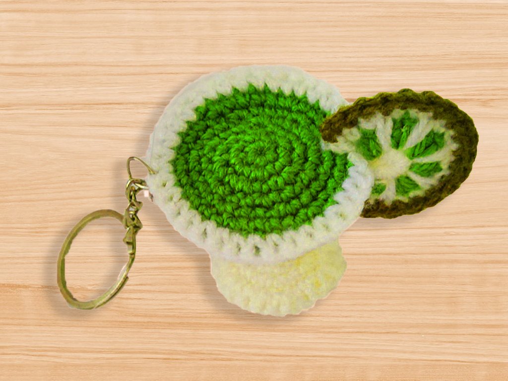 Gehäkelter Schlüsselanhänger in Limettenform mit Metallring auf Holz